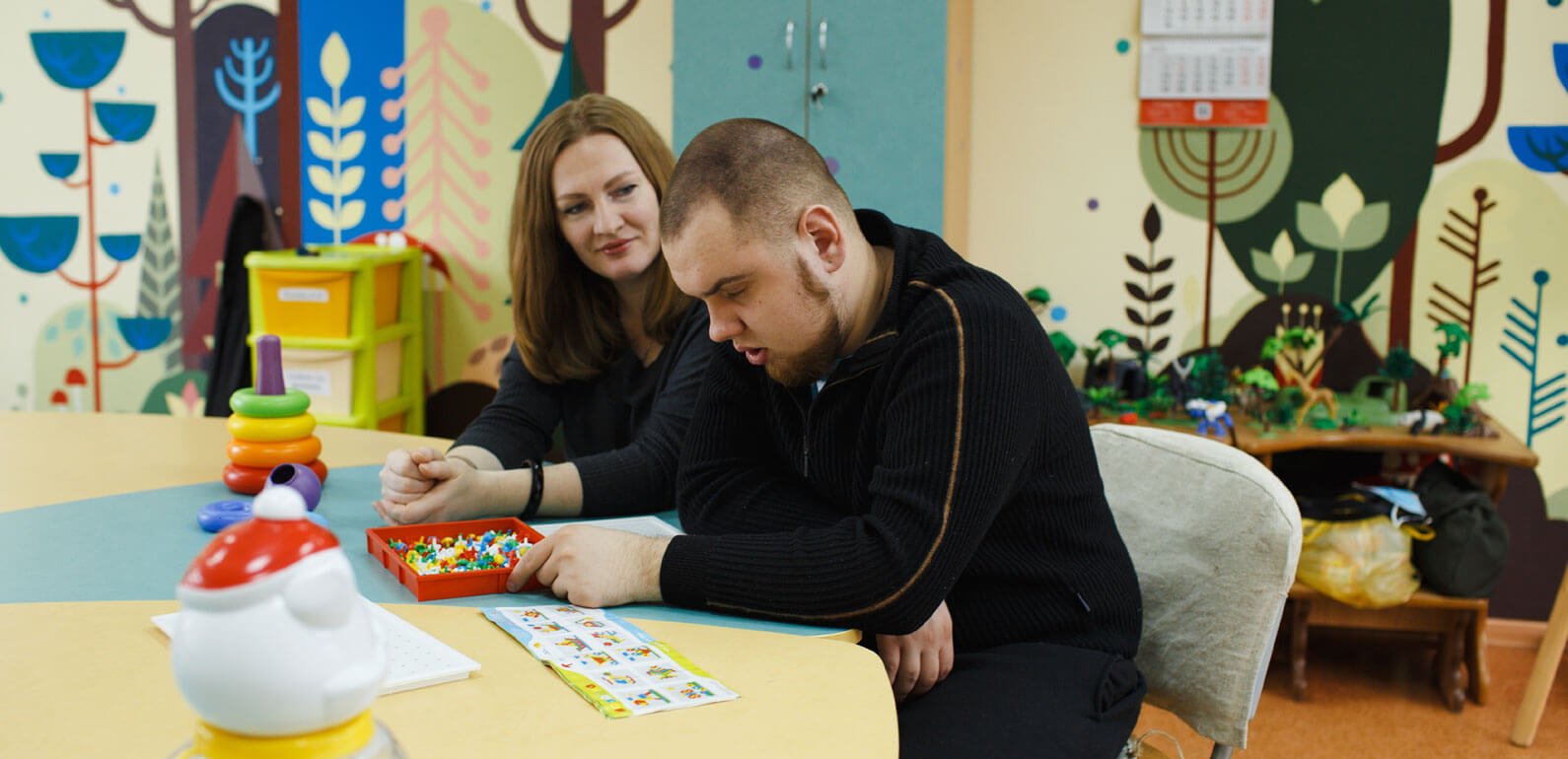 Support worker sat next to adult with learning disabilities