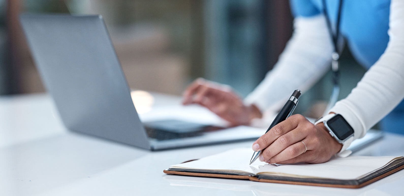Health worker making notes while using a laptop