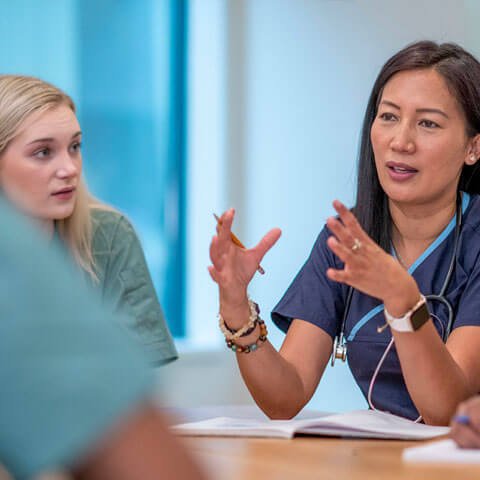 Female health worker sat at a table with other female health workers discussing a subject