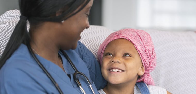Healthcare worker looking and smiling at a child who is smiling back at them